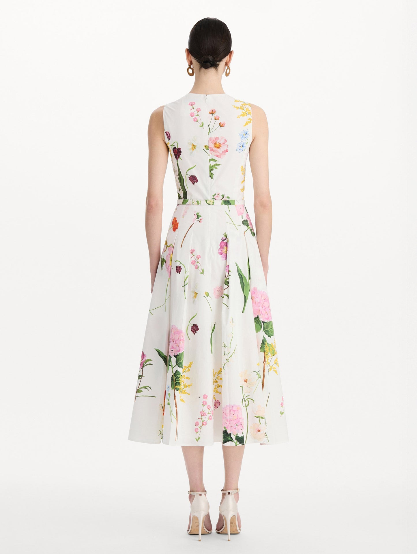 The model is wearing the mixed botanical cotton poplin sleeveless dress with an all-over floral print in white multi. Back view.