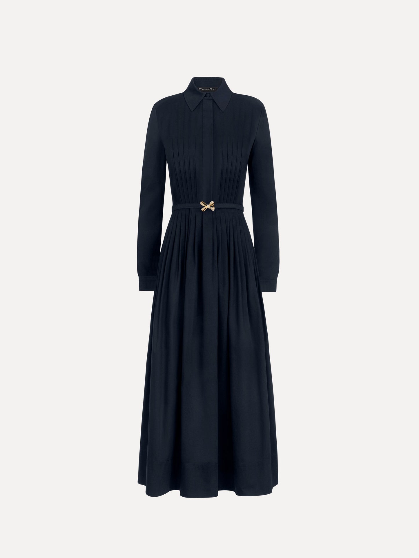 The model is wearing the bow belt cotton stretch twill dress with a collared neckline and long sleeves in the color navy.