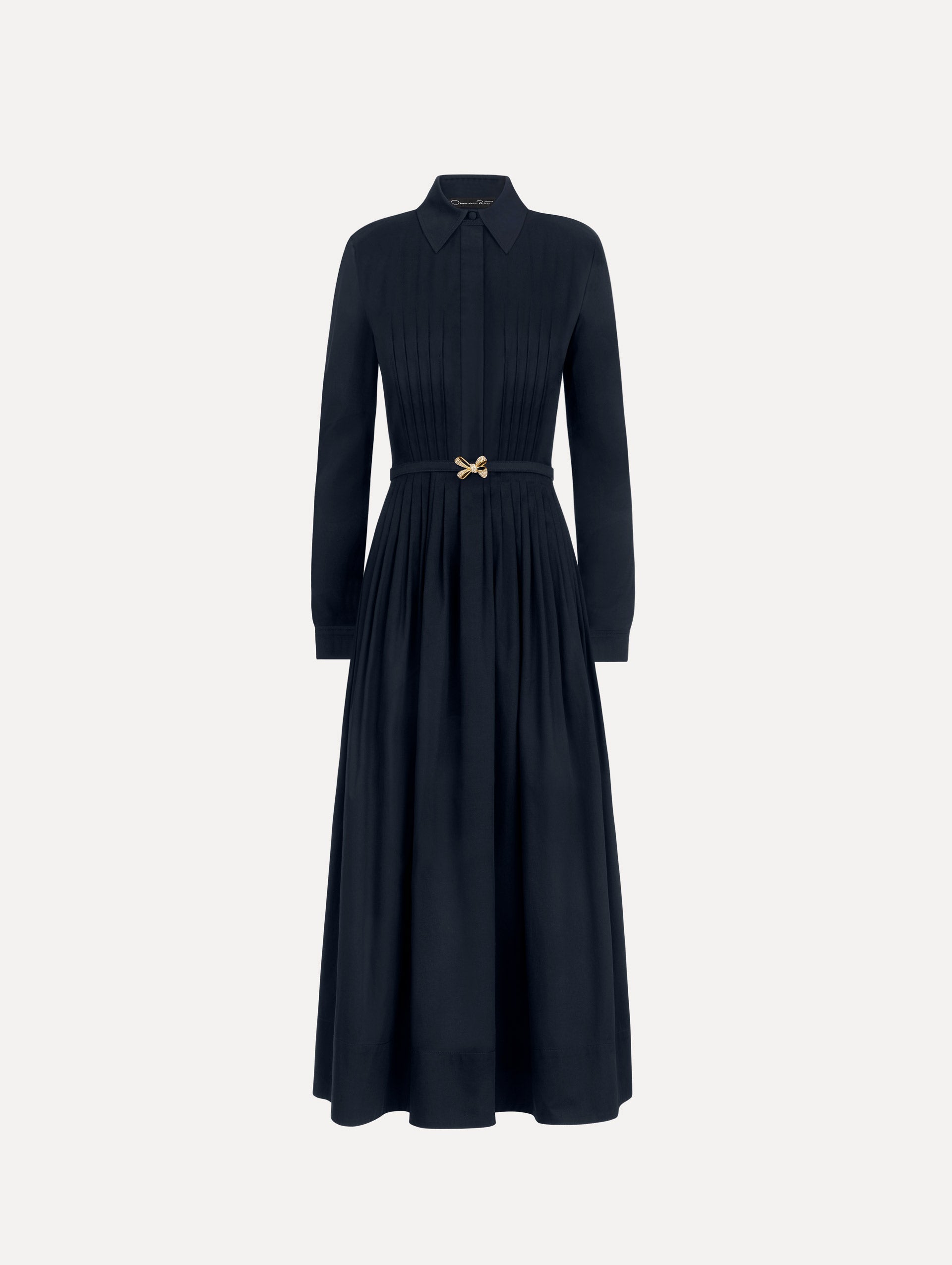 The model is wearing the bow belt cotton stretch twill dress with a collared neckline and long sleeves in the color navy.