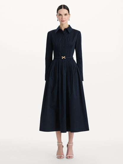 The model is wearing the bow belt cotton stretch twill dress with a collared neckline and long sleeves in the color navy. Front view.