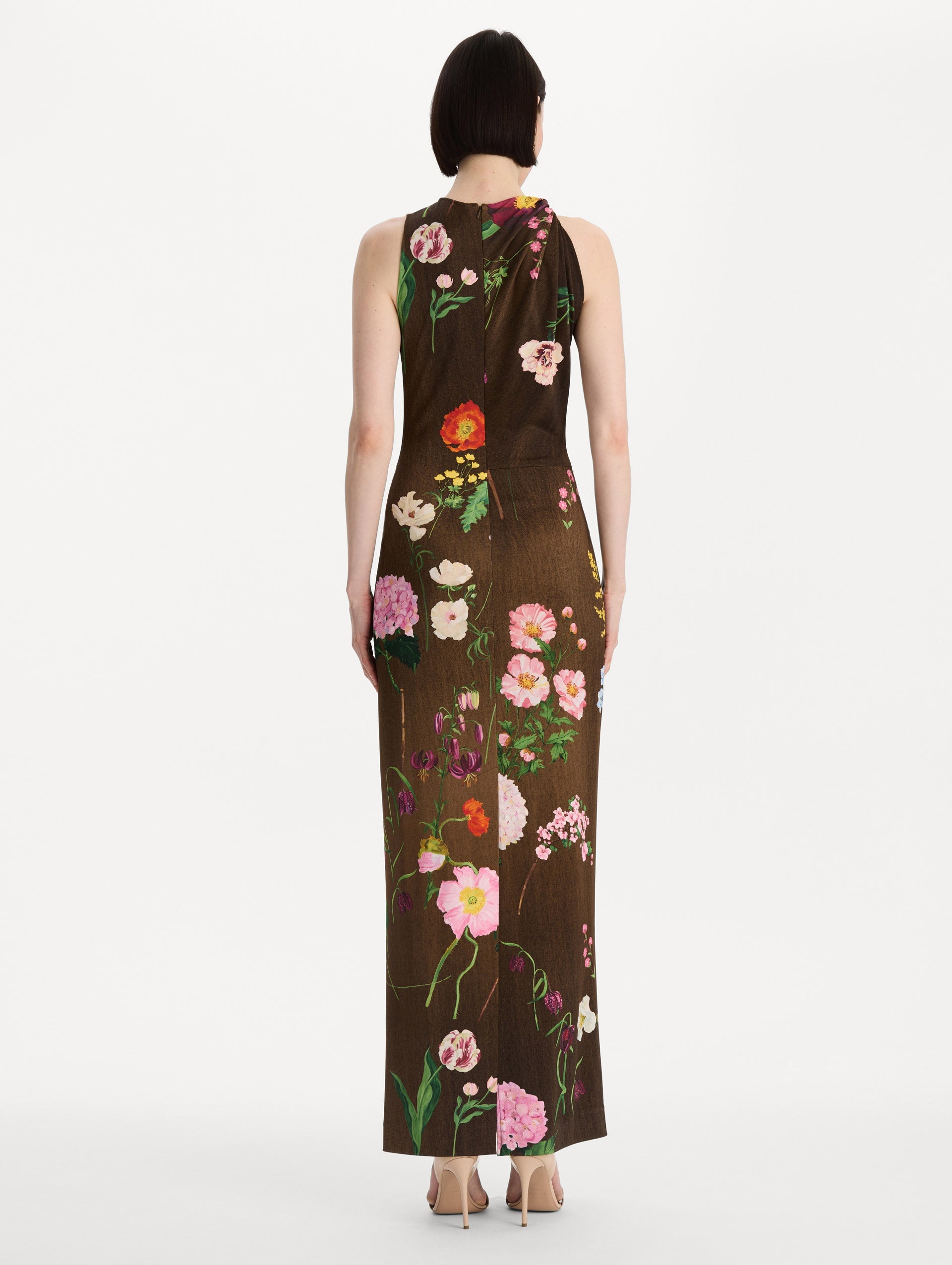 The model is wearing the mixed botanical Milano jersey dress with a sleeveless silhouette in a brown multi palette. Back view.