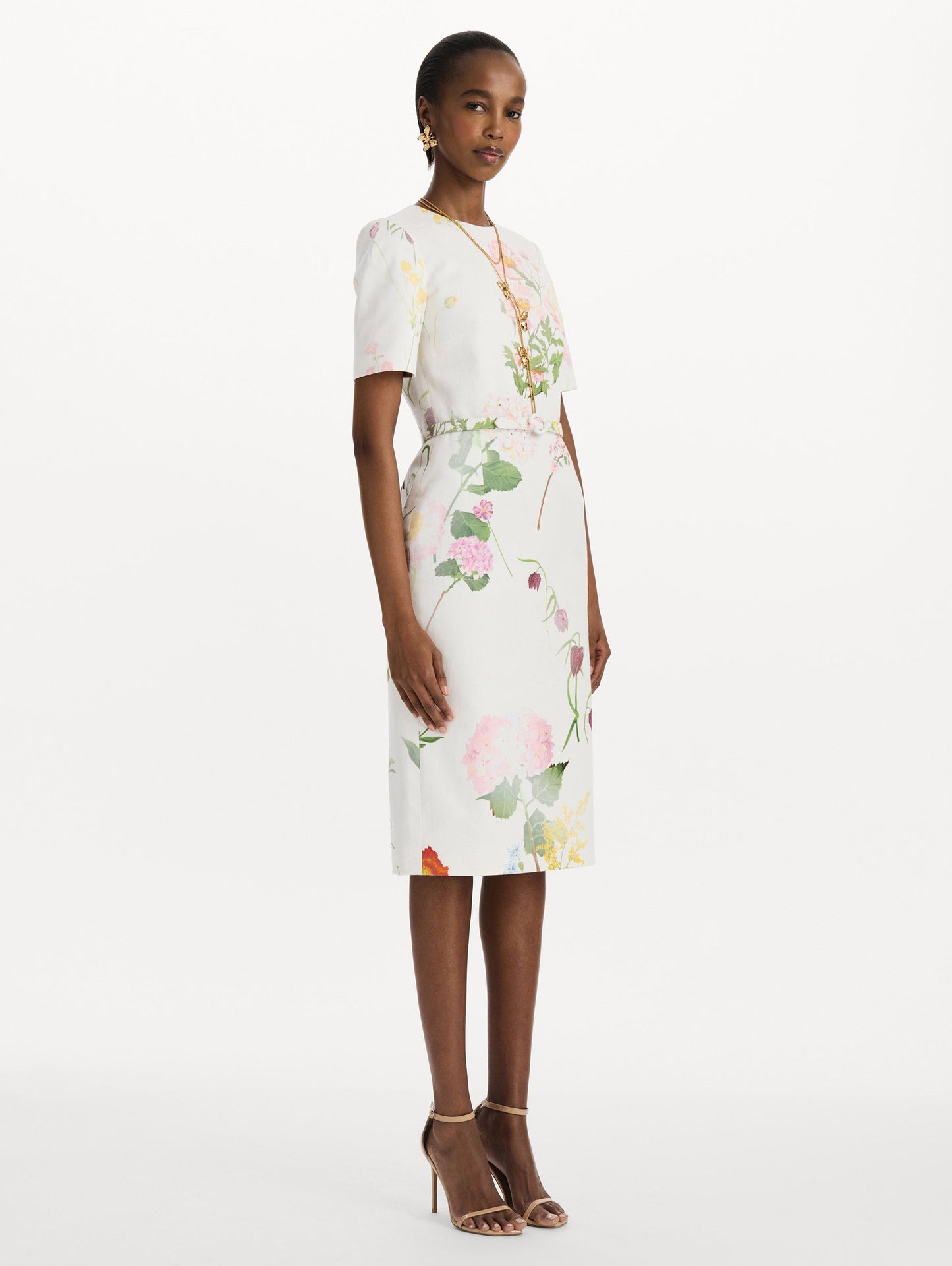 The model is wearing the faded mixed botanical denim dress with midi sleeves and a washed floral print in white multi. Side view.