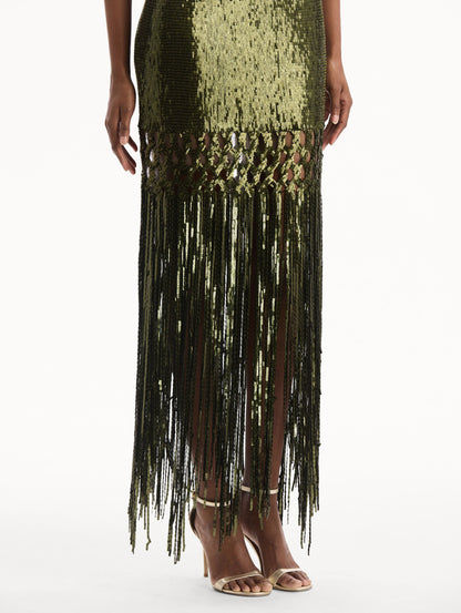 The model is wearing the Sequin Fringe Gown in green. Featuring a strapless neckline, fitted silhouette, and an open lattice detail cascading into a fringe skirt. Detail View.