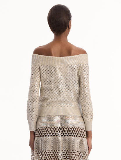 The model is wearing the Silver Foil Off-Shoulder Pullover. Featuring a lattice knit pattern, off-the-shoulder neckline, long sleeves, and ribbed trims. Back View.