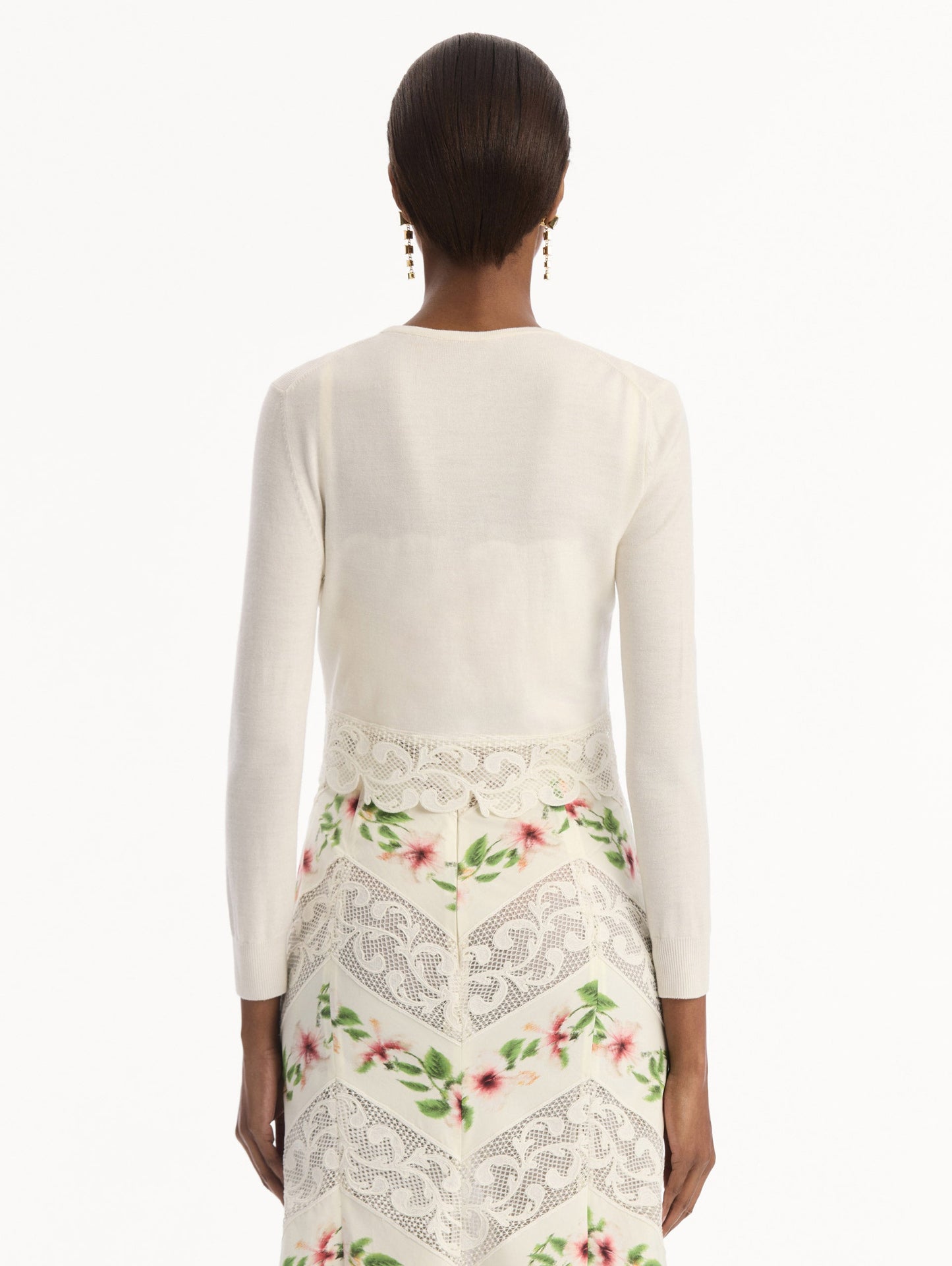 The model is wearing the Chiné Hibiscus Threadwork Cropped Cardigan in Ivory. Featuring a threaded Chiné hibiscus and intricate guipure lace trim. Back View.
