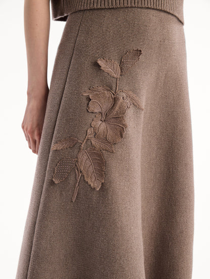 The model is wearing the Hibiscus Embroidered Knit Skirt. Featuring a softly flared silhouette and midi length. Detail View.