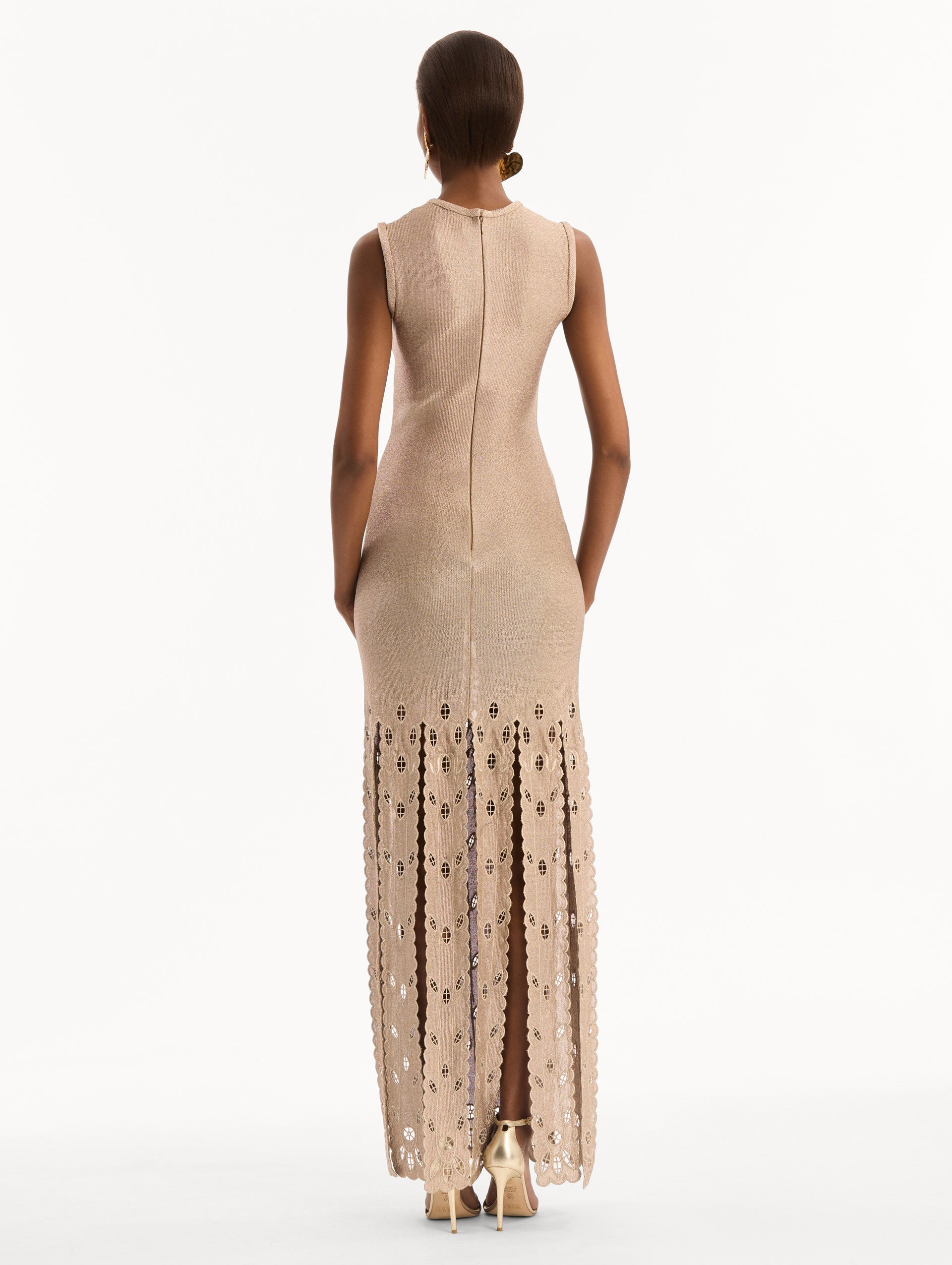 The model is wearing the Pineapple Fringe Metallic Jersey Dress. Featuring shimmering metallic jersey fabrication, a body-skimming silhouette, and pineapple-inspired fringe along the hem. Back View.