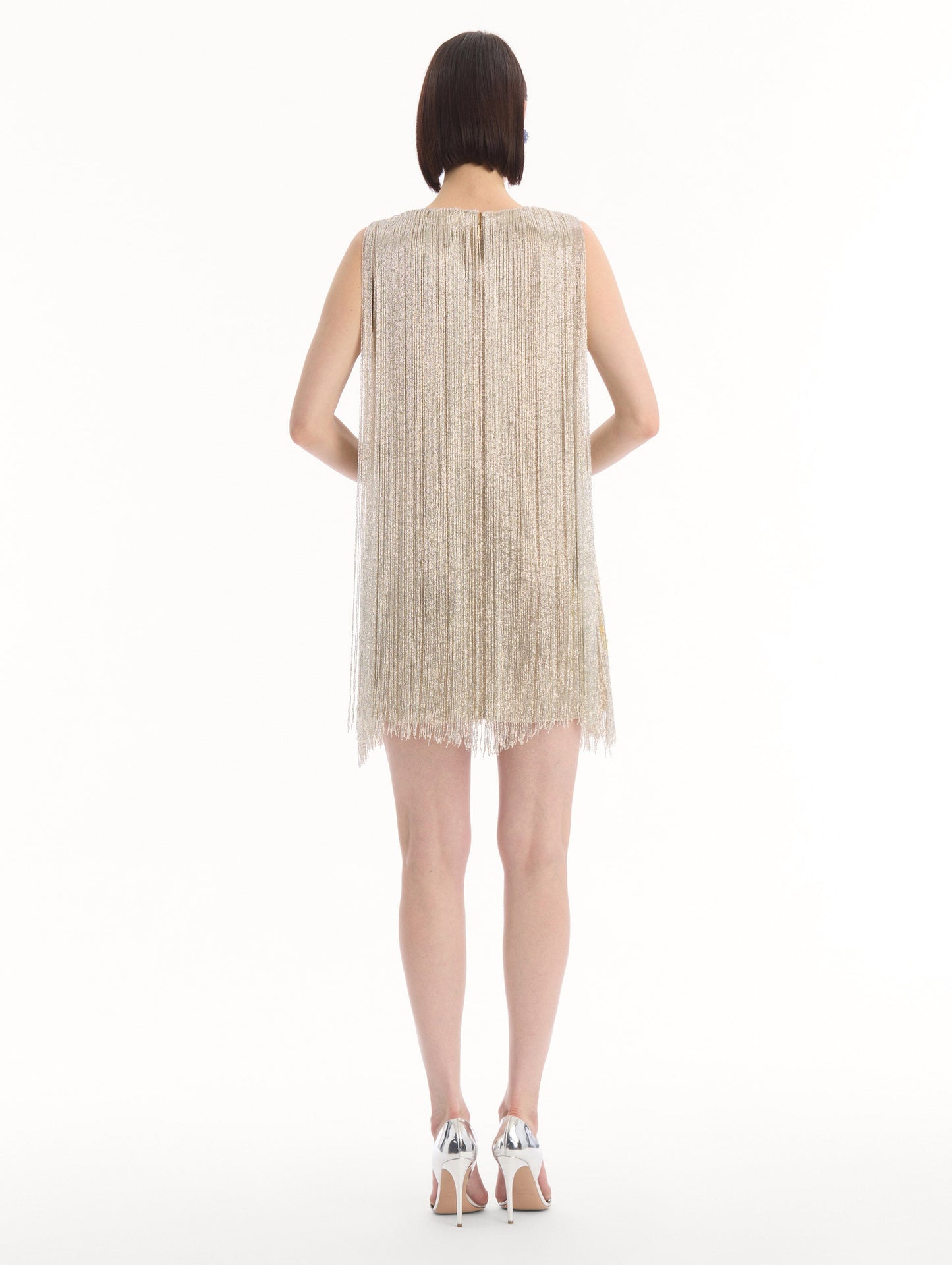 The model is wearing the Chiné Hibiscus Beaded Fringe Shift Dress. Featuring layers of beaded fringe and mini length. Back View.