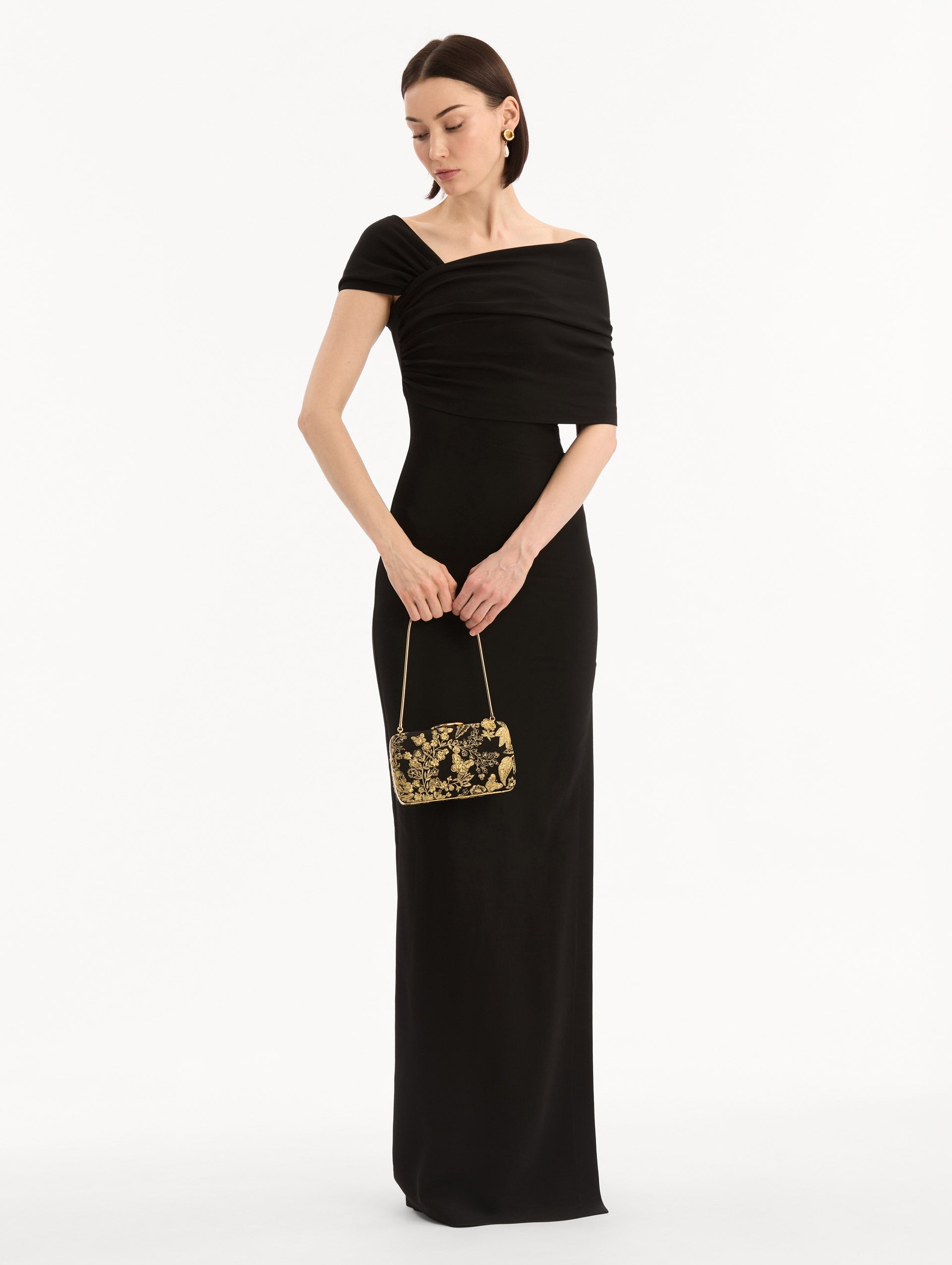 The model is wearing the Butterfly Embroidered O Minaudière in Black Satin with Gold Butterfly Embroidery. Full-Body View.
