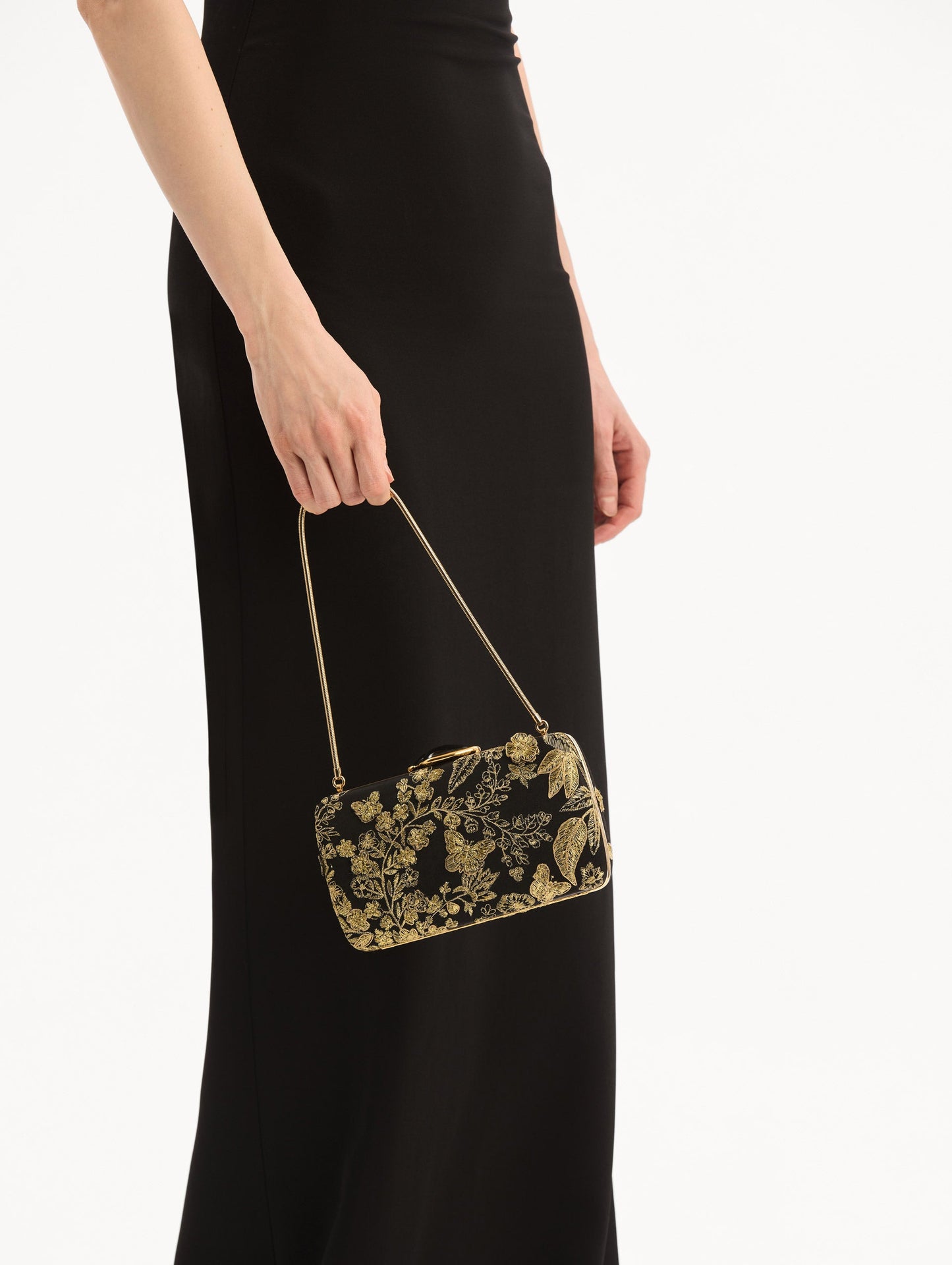 The model is wearing the Butterfly Embroidered O Minaudière in Black Satin with Gold Butterfly Embroidery. Detail View.