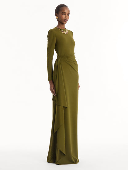 The model is wearing the Drape-Detail Jersey Gown in olive green. Featuring long sleeves, a body-skimming silhouette, gathered detail at waist, and long skirt. Side View.