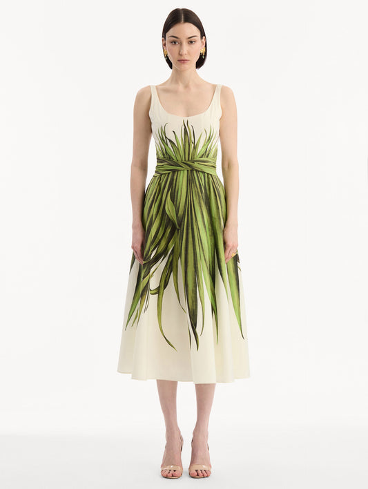 The model is wearing the Palm Leaves Cotton Poplin Dress. Featuring a scoop neckline, tank straps, cinched waist, and midi length. Front View.