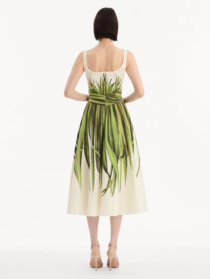 The model is wearing the Palm Leaves Cotton Poplin Dress. Featuring a scoop neckline, tank straps, cinched waist, and midi length. Back View.