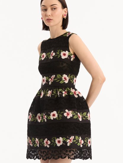 The model is wearing the Chiné Hibiscus Striped Faille Dress in Black. Featuring woven hibiscus motifs alternating with panels of faille and guipure lace, creating a striped pattern. Mini length. Detail View.