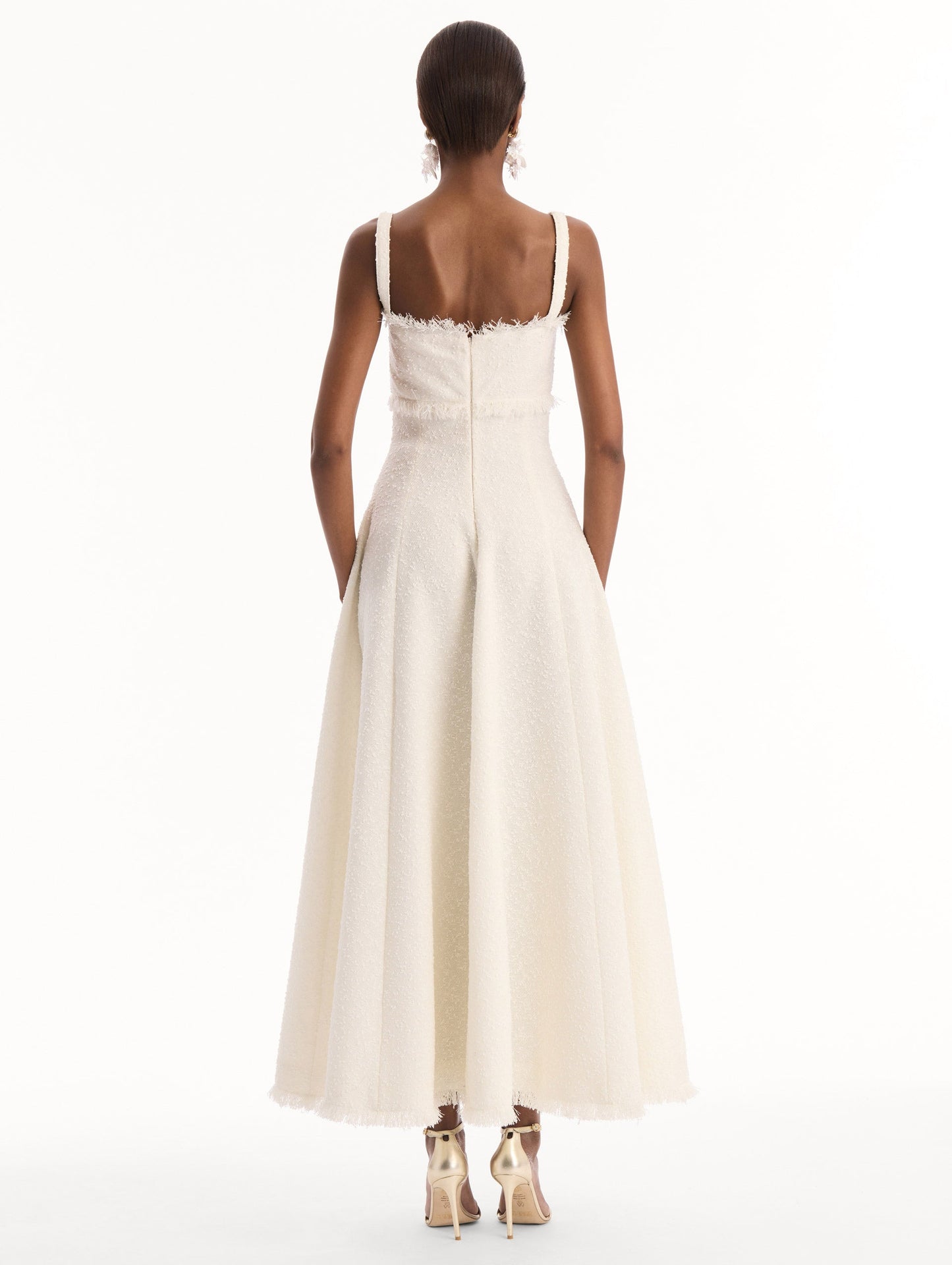 The model is wearing the Slub Wool Tweed Midi Dress in Ivory. Featuring a softly structured silhouette and curved neckline accented with delicate fringe detailing. Back View.