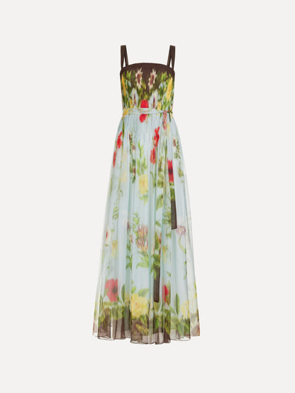 The Dominican Mixed-Floral Silk Chiffon Gown in light blue printed with an array of Dominican florals and brown at the trims. Featuring a pleated bodice, tank straps, tie at waist, and long, flowing skirt. Front View.