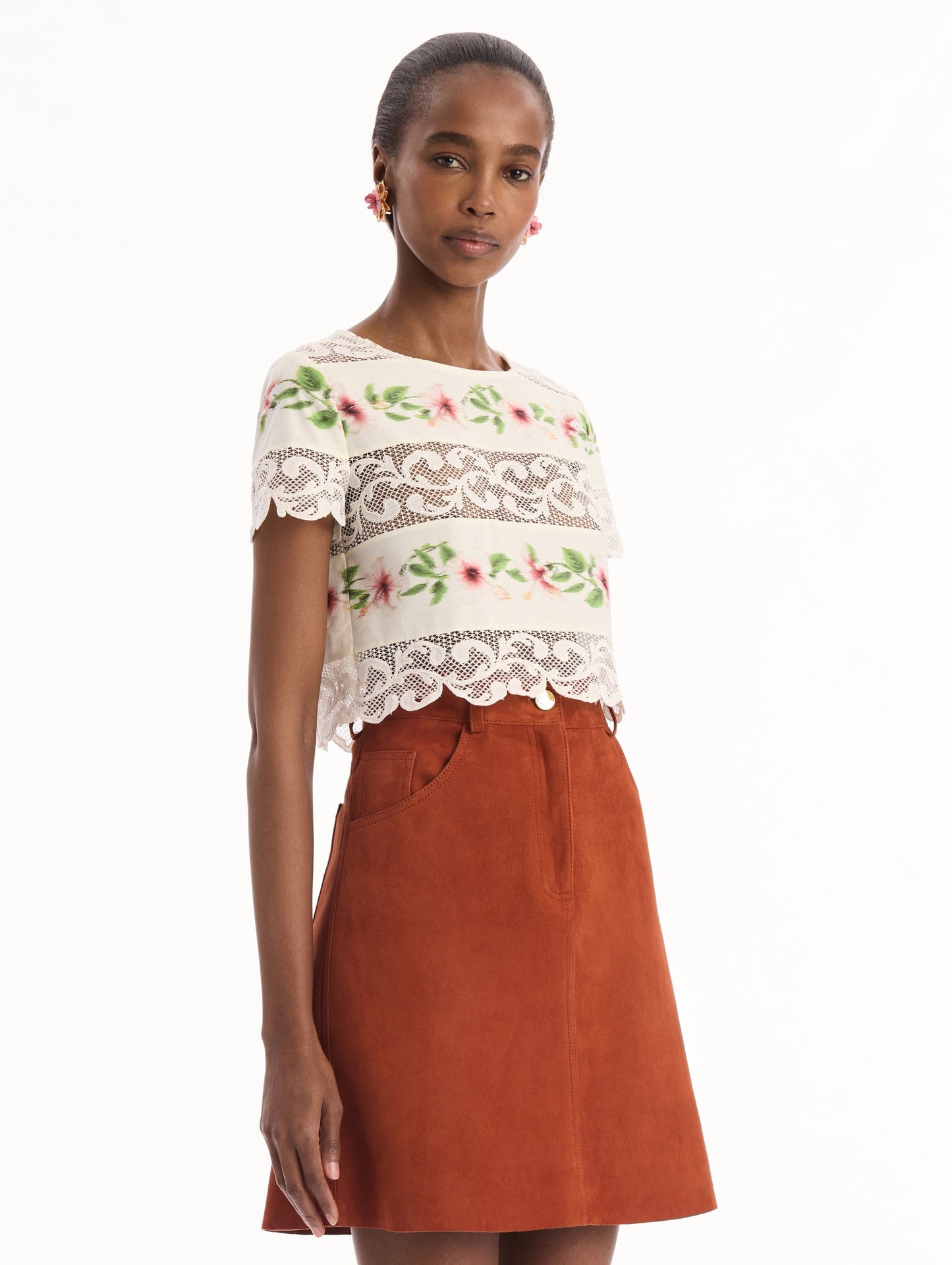 The model is wearing the chiné hibiscus striped cotton poplin blouse with guipure lace panels and a striped floral pattern in the color ivory. Side view.