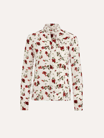 The Hibiscus Silk Chiffon Blouse in white printed with red hibiscus florals. Featuring a tie at neckline, long sleeves, and tailored silhouette. Front View.