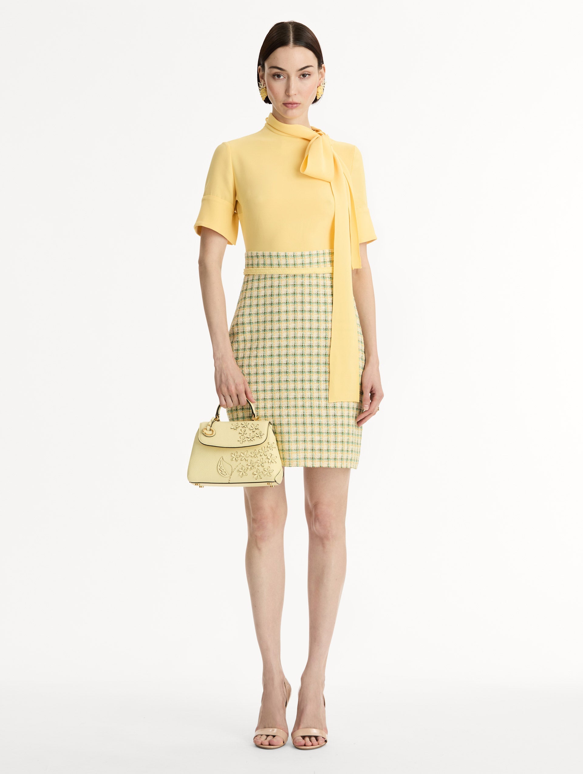 The Mini Poppy in yellow with floral cutout designs and gold hardware. Front View.