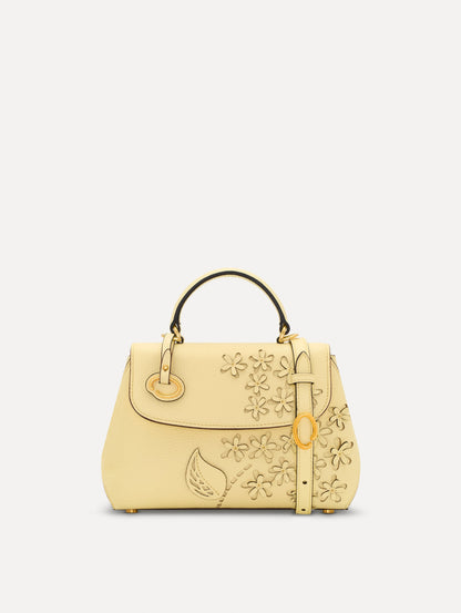 The Mini Poppy in yellow with floral cutout designs and gold hardware. Front View.