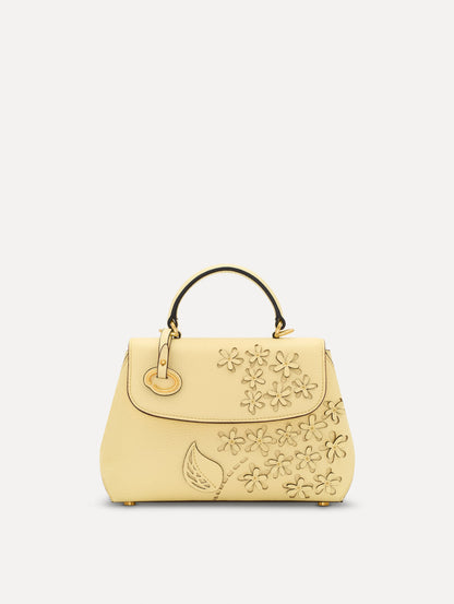 The Mini Poppy in yellow with floral cutout designs and gold hardware. Front View.