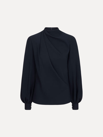 The model is wearing the Draped Georgette Blouse in the color Navy. Featuring silk georgette, a draping mock-neckline, and long, billowed sleeves. Front View.