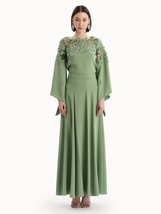 The model is wearing the Silk Georgette Midi Skirt in the color green featuring a high-waist and classic, flowing skirt. Front View.