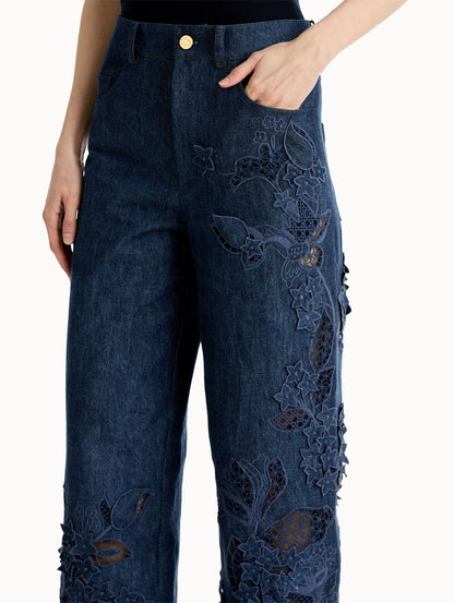 Mid-rise denim pants with intricate porcelain flower threadwork and cutout detailing. Side View, Close Up.