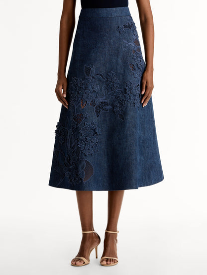 High waisted denim skirt with intricate porcelain flower threadwork. Classic A-line silhouette. Mid length. Front View.