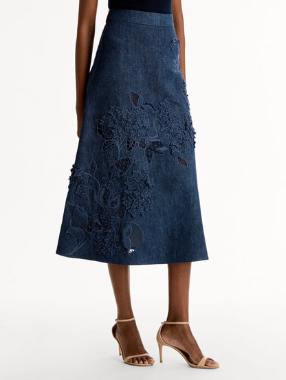 High waisted denim skirt with intricate porcelain flower threadwork. Classic A-line silhouette. Mid length. Side View.