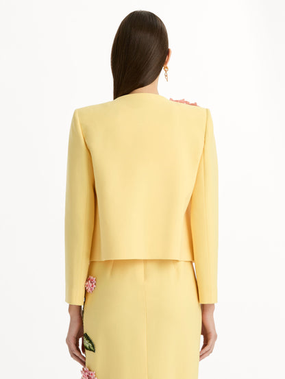 Cropped yellow jacket tailored from double-faced stretch wool and finished with sculptural porcelain flower embroidery at the shoulder. Back View.