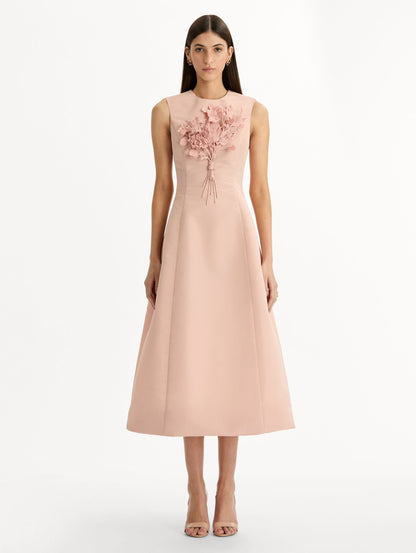 Blush pink cocktail midi dress. Centered, three dimensional hand-embroidered bouquet creating the illusion of a bouquet held close to the heart. Halter neck with flared skirt. Front View.