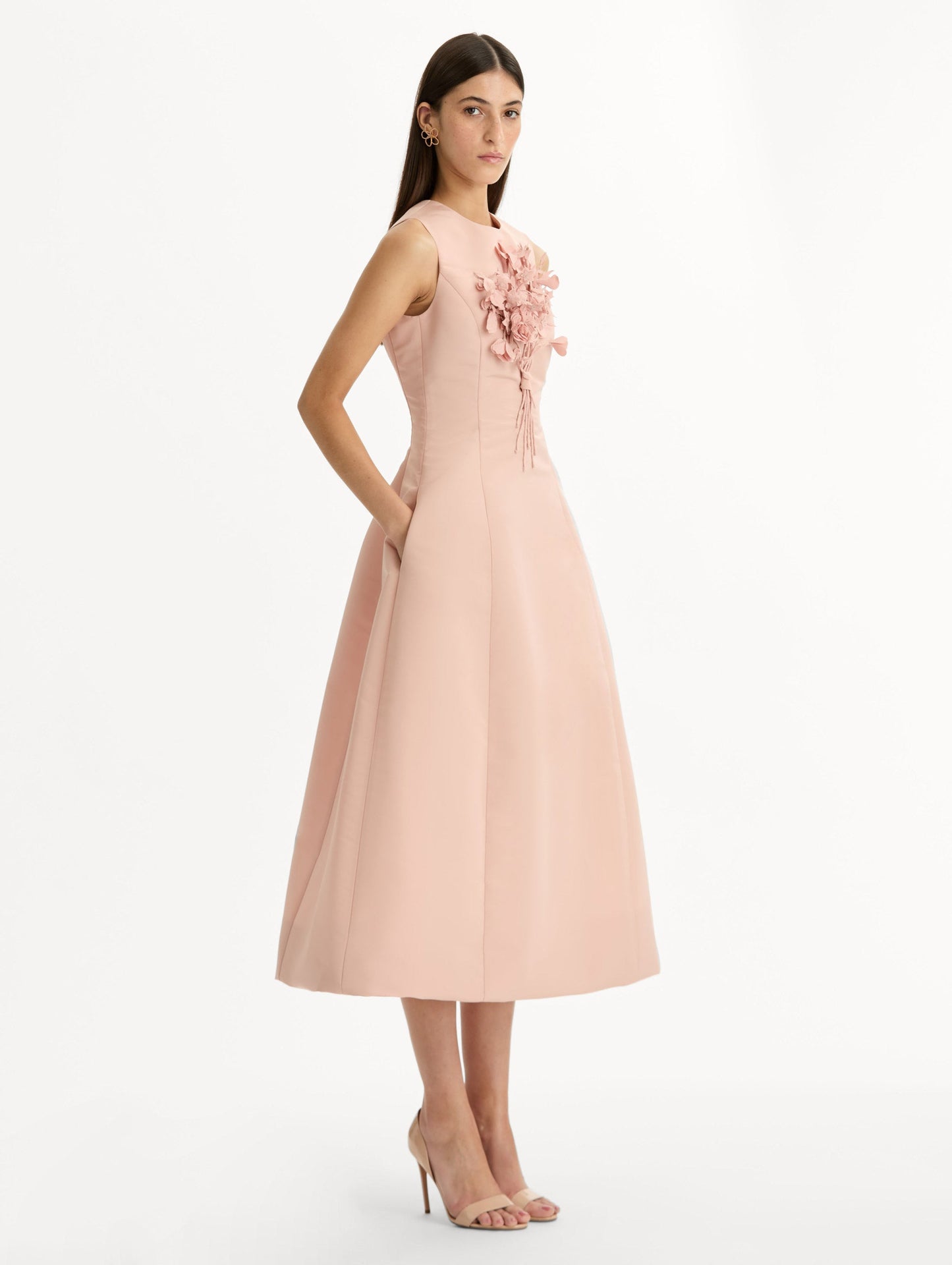 Blush pink cocktail midi dress. Centered, three dimensional hand-embroidered bouquet creating the illusion of a bouquet held close to the heart. Halter neck with flared skirt. Side View.