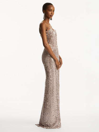 Model wearing soft pink strapless sequin wave embellished gown. Side view
