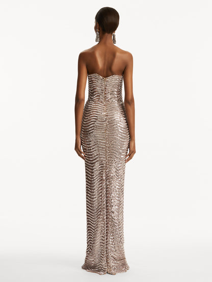 Model wearing soft pink strapless sequin wave embellished gown. Back view