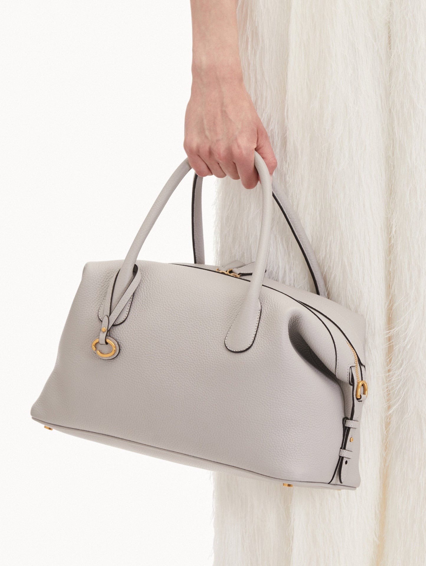Model holding The Dahlia Leather Handbag in Grey with O logo tag around the Top Handle Front View