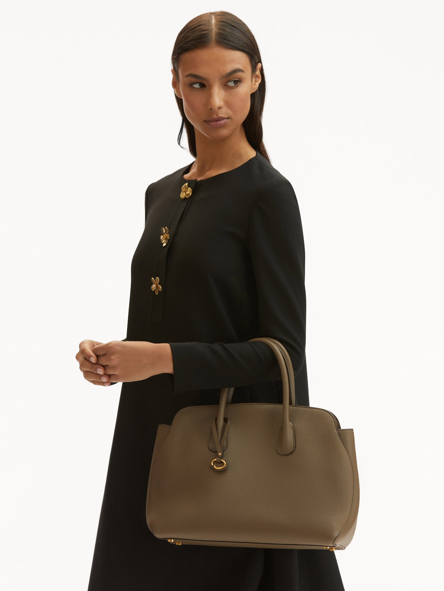 Model in black dress holding The Ivy leather bag in taupe. Front View