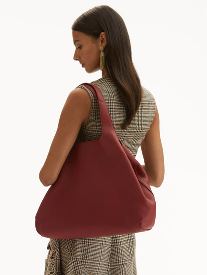 Model in plaid dress wearing The Topaz Tote in red Front View