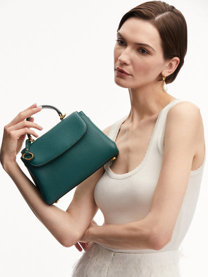 Model holding The Mini Poppy Leather Handbag in Green with O logo Tag around the Top Handle, and Detachable Shoulder Strap. Front View