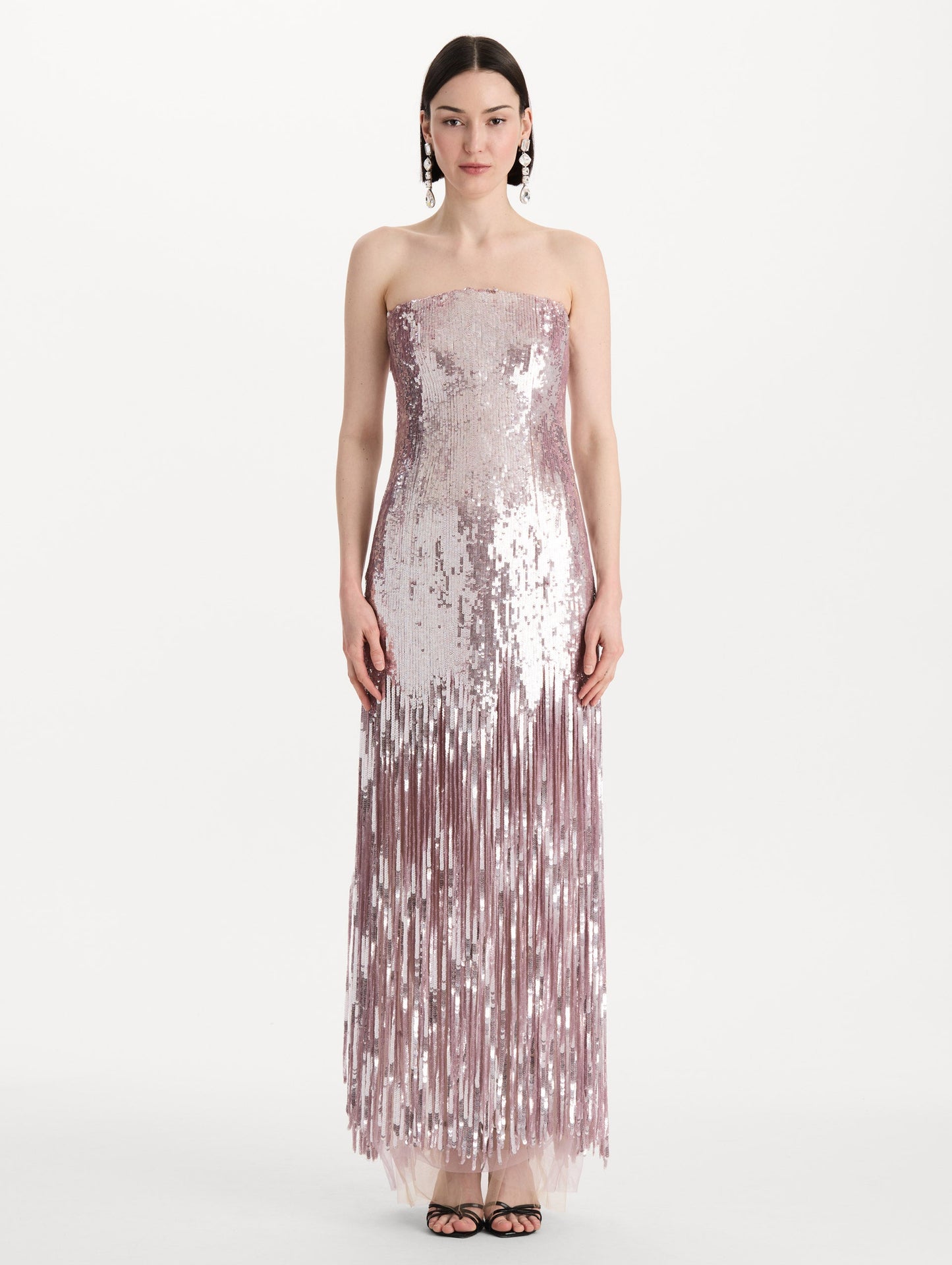 The model is wearing the Sequin Fringe Strapless Gown in the color tulip pink featuring a strapless silhouette, all-over sequins, and fringe skirt. Front View.