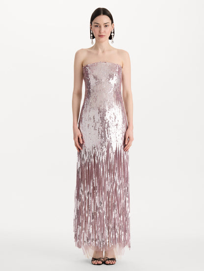 The model is wearing the Sequin Fringe Strapless Gown in the color tulip pink featuring a strapless silhouette, all-over sequins, and fringe skirt. Front View.