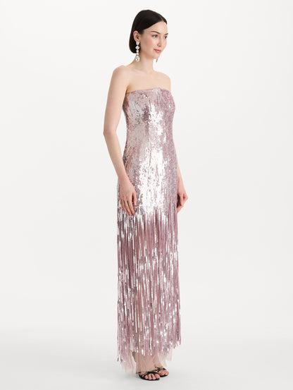 The model is wearing the Sequin Fringe Strapless Gown in the color tulip pink featuring a strapless silhouette, all-over sequins, and fringe skirt. Side View.