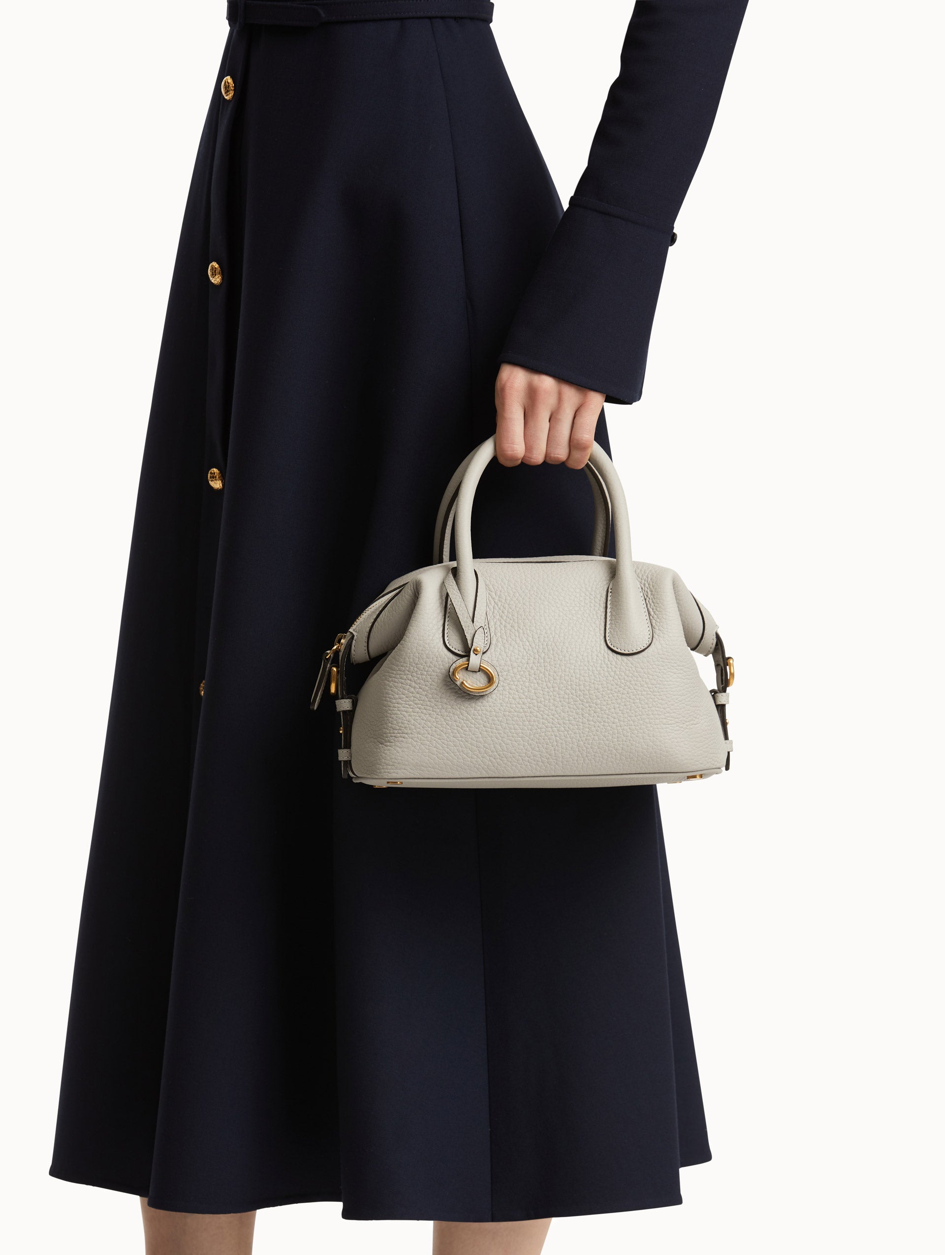 Pearl Grey Handbag, with Top Handle, Crossbody Strap, and Oscar logo around the Handle. Front View.