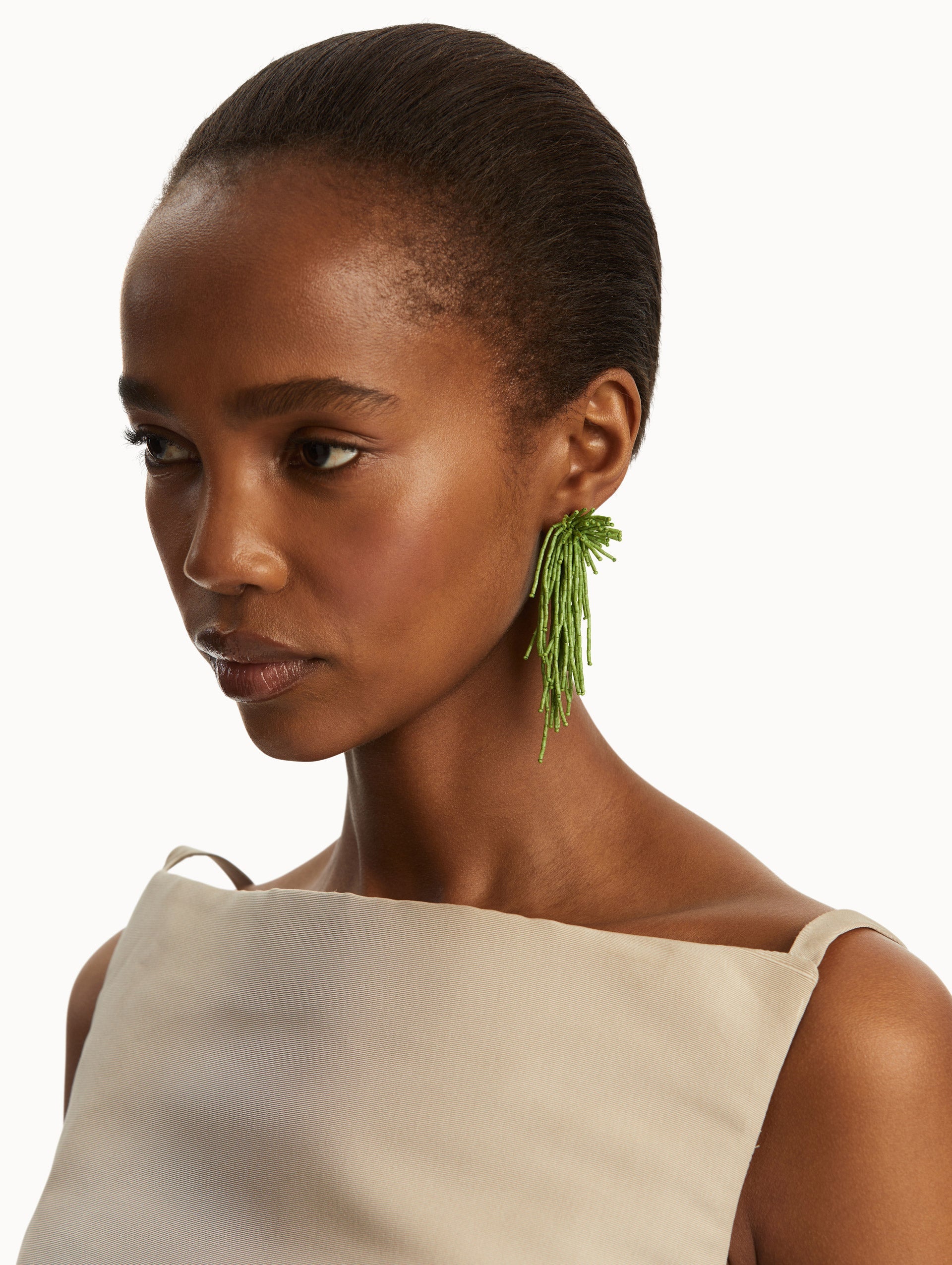 The model is wearing the Firework Tassel Earrings in the color fern.