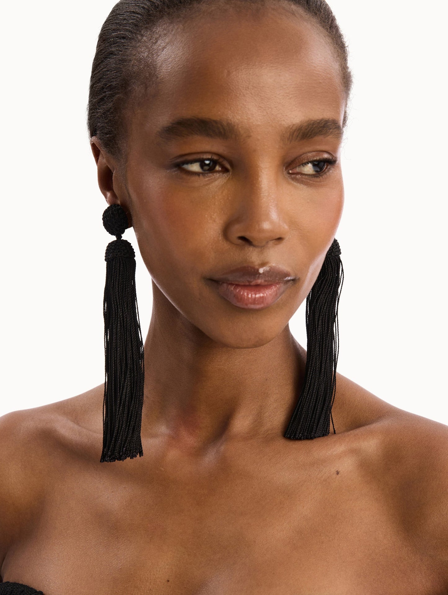 The model is wearing the Silk Rope Tassel Clip-On Earrings in Black. Detail View.