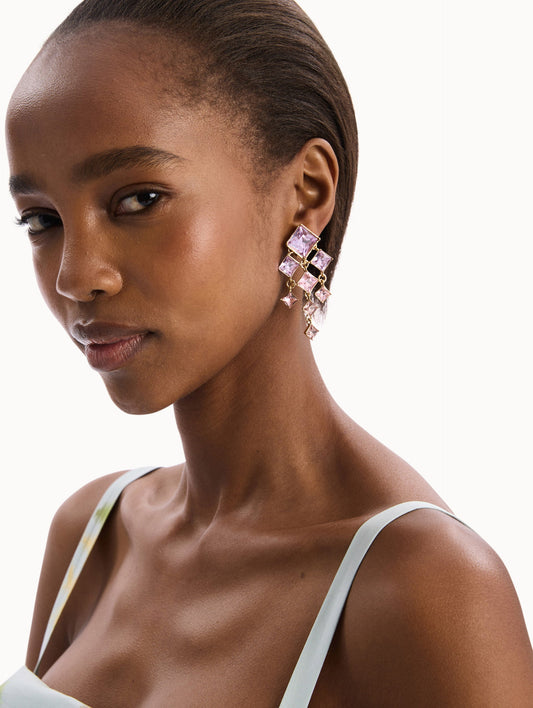 The model is wearing the Square-Cut Rhinestone Chandelier Clip-On Earrings in Violet. Detail View.