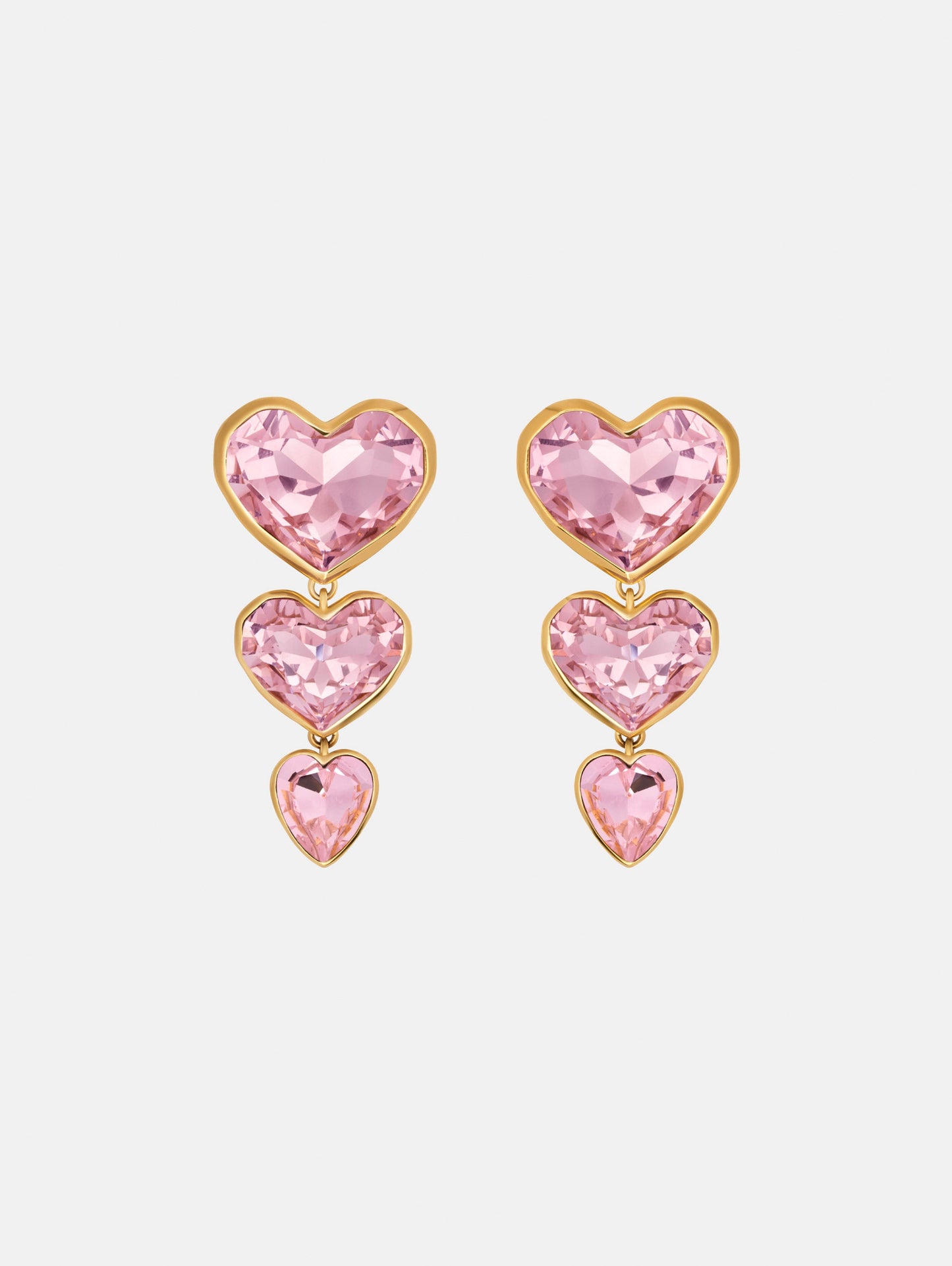 The Crystal Heart Drop Clip-On Earrings in Pink. Three vertically connected hearts with gold rims. Front View.