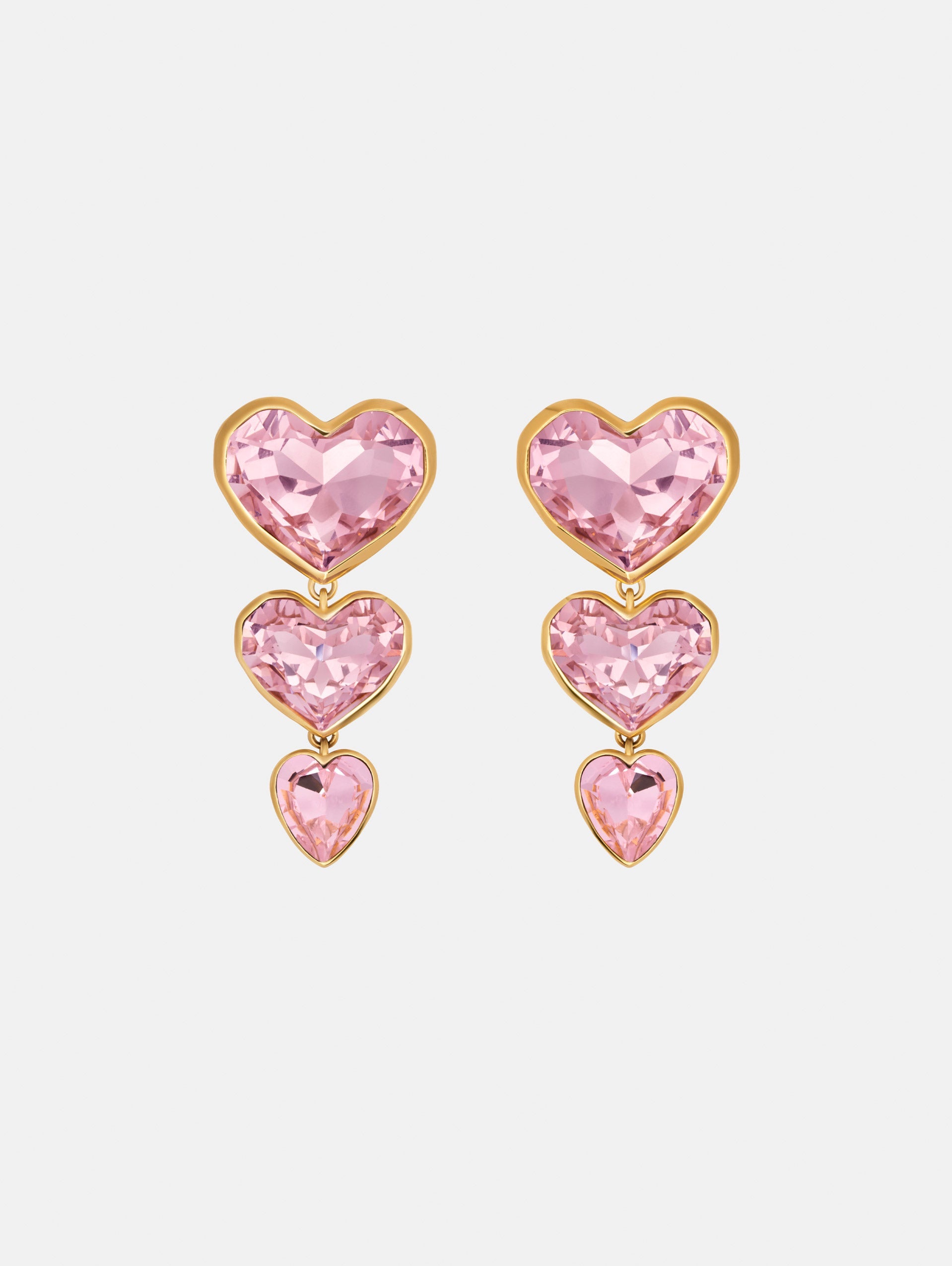 The Crystal Heart Drop Clip-On Earrings in Pink. Three vertically connected hearts with gold rims. Front View.