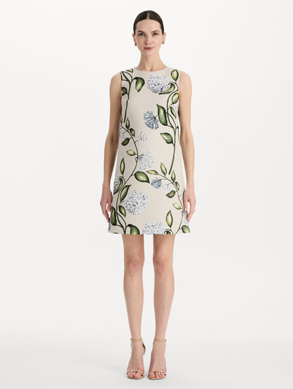 The model is wearing the Porcelain Flower Faille Shift Dress in white featuring a mini-length and printed floral motif. Front View.