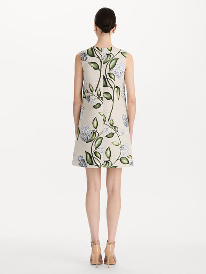 The model is wearing the Porcelain Flower Faille Shift Dress in white featuring a mini-length and printed floral motif. Back View.